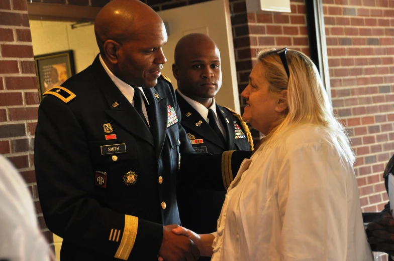 a woman and two men shake hands in a room