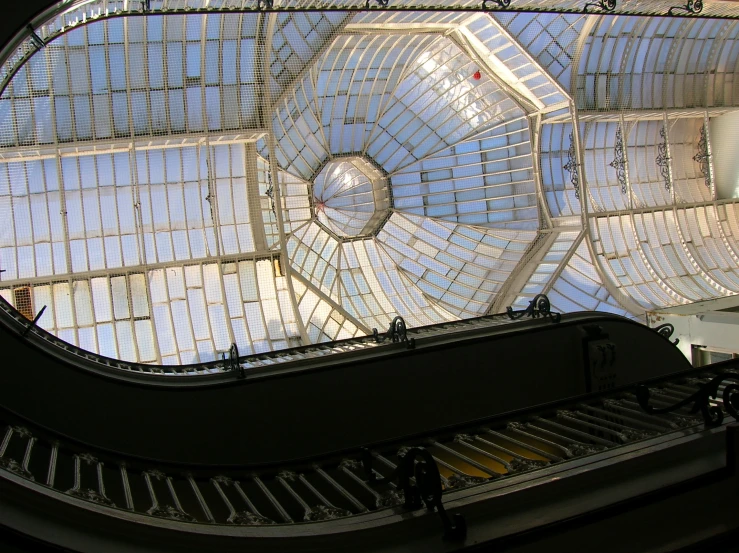 an escalator with lots of glass windows at the top