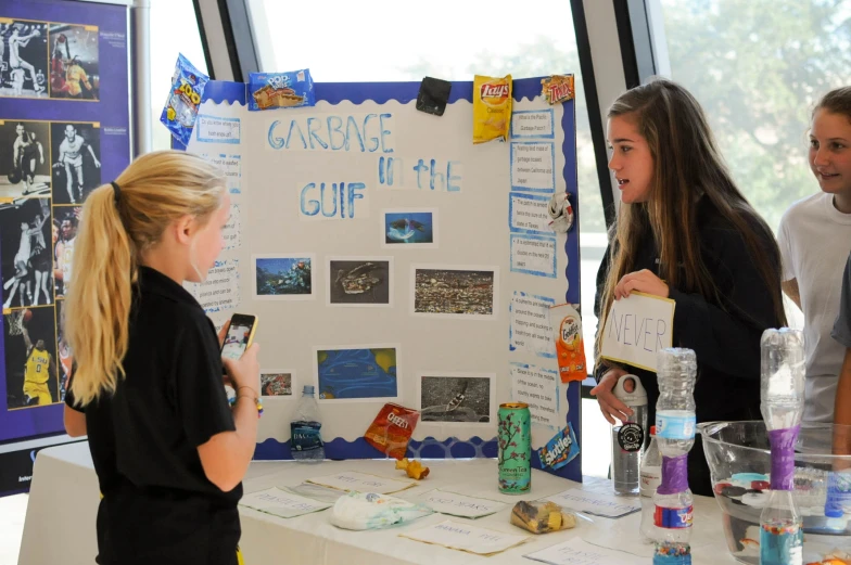 four students have their own poster displayed at a table
