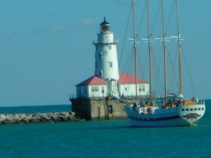 a tall boat in the ocean next to a lighthouse