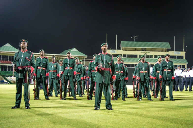 military men marching down an empty field with lights on at night