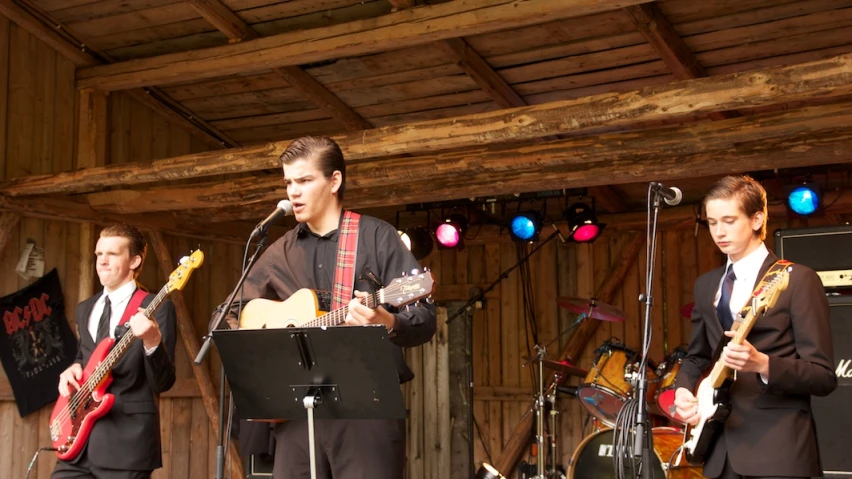 a band playing musical with people standing around