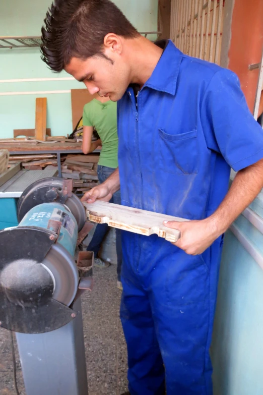 the young man works with a piece of wood on an object