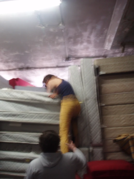 two men in a storage area trying to get some mattresses