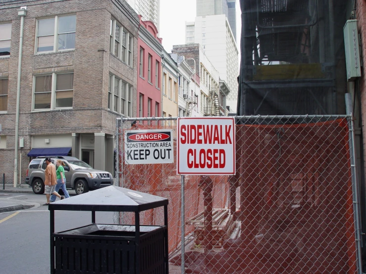 street signs are placed on the fence surrounding the buildings