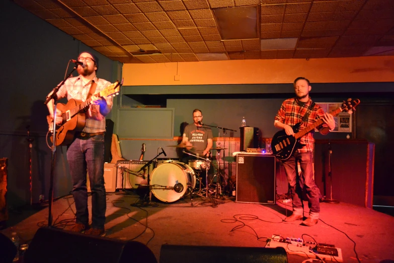 three men playing guitars and singing into microphones