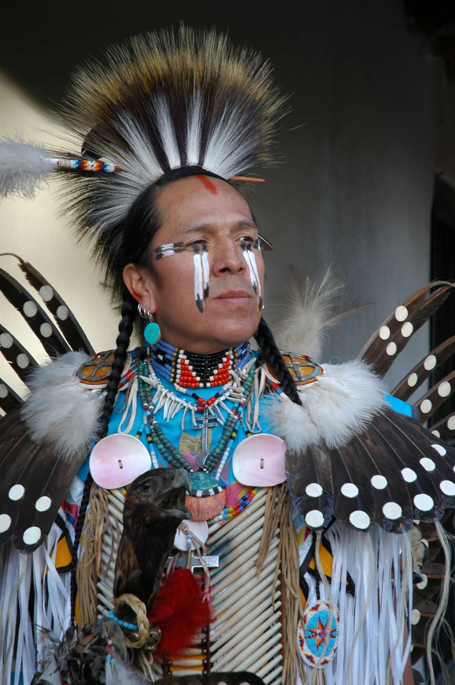a native indian man with feather headdress stands in front of a building