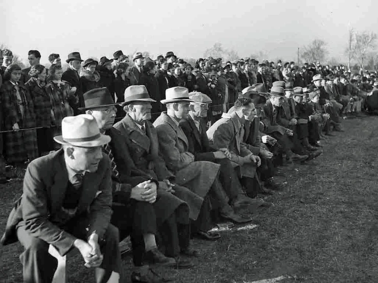 a crowd of people sitting and standing in a field