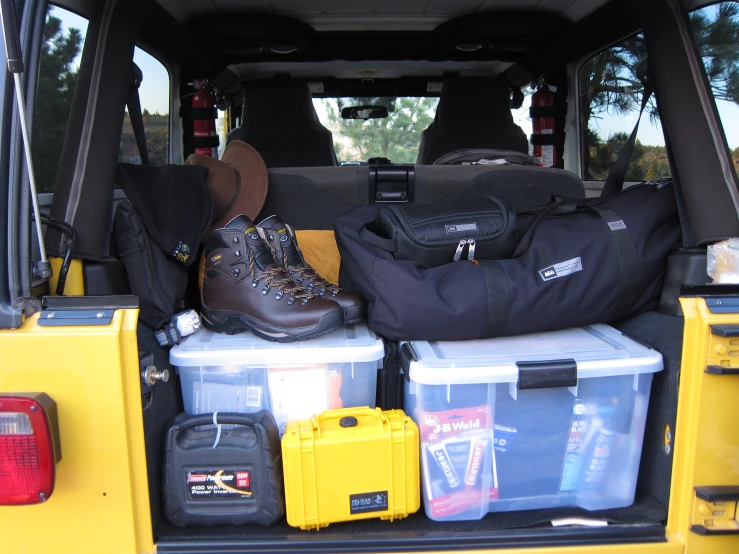 some suitcases and other items are in the back of a yellow vehicle