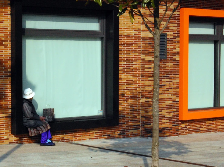 a woman sitting on a curb next to windows