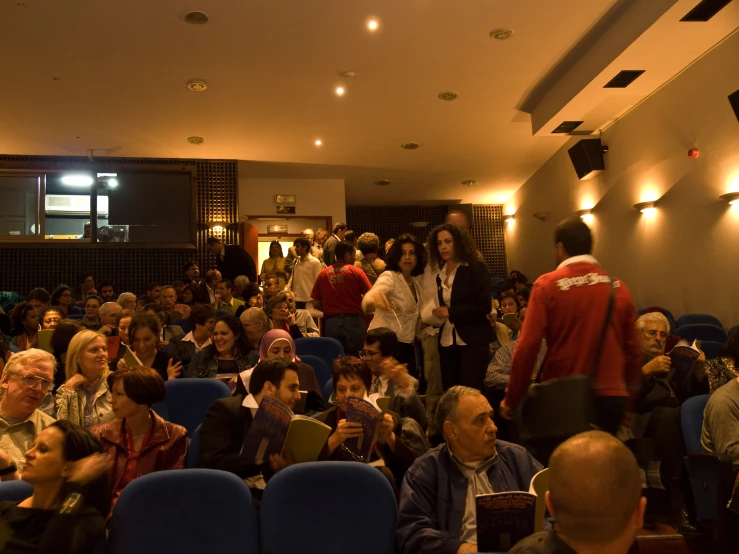 people in an auditorium are sitting and talking