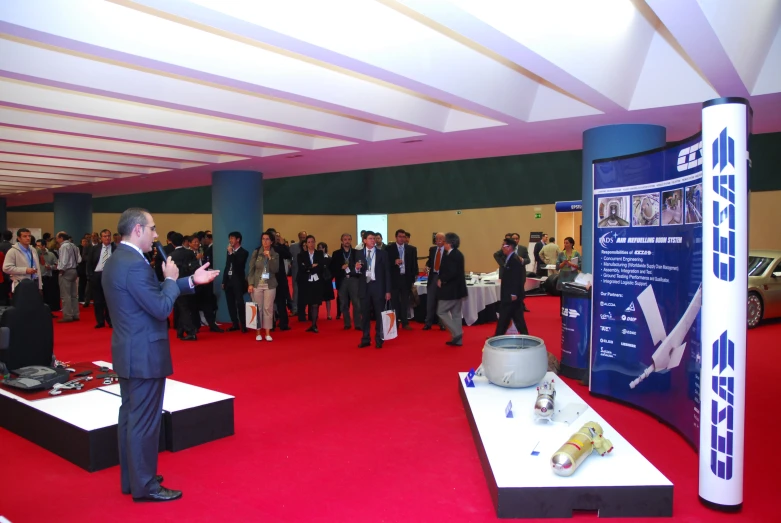 a large crowd of people and businesspeople stand around a display in a building