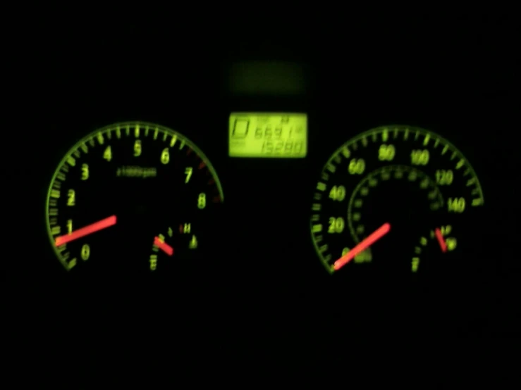 the dashboards and gauges on a car illuminated in the dark