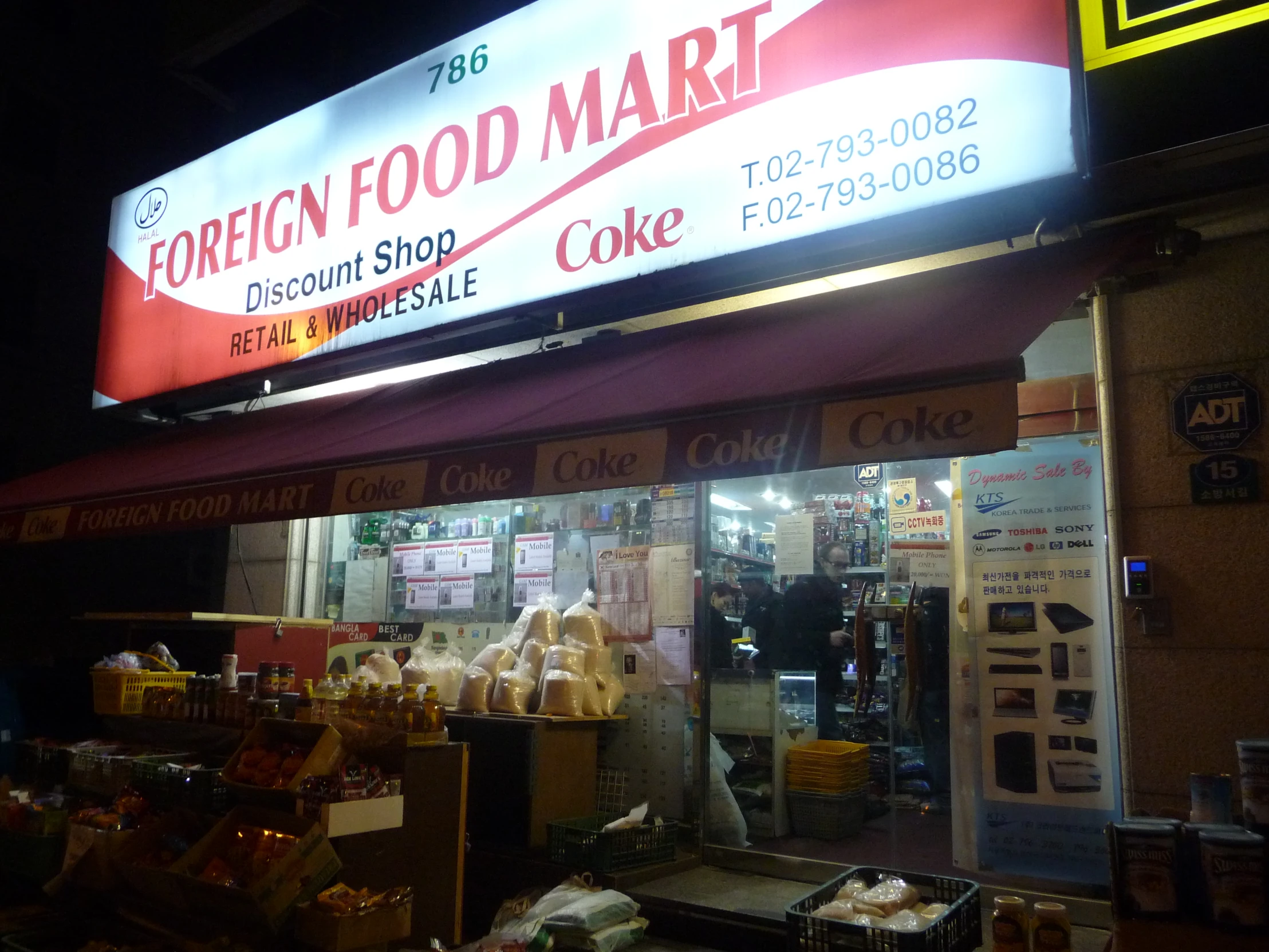 a grocery storefront with neon signage at night