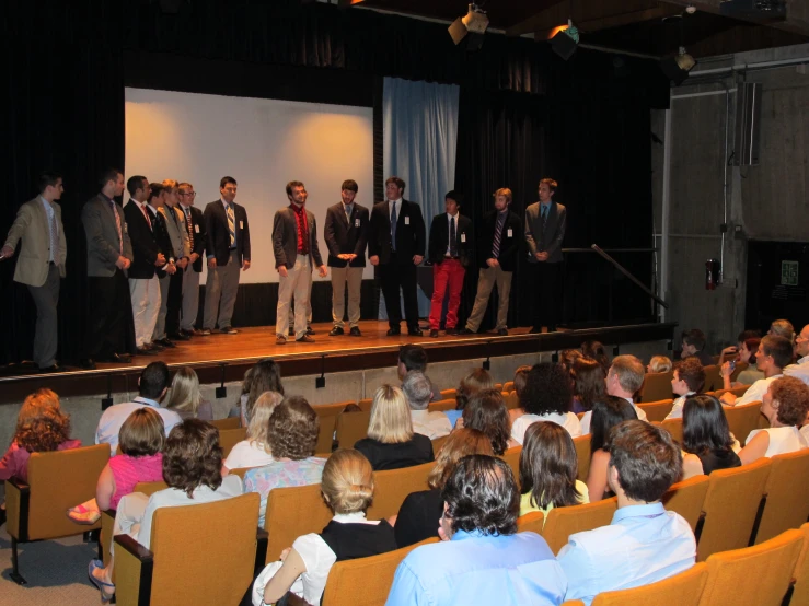 the men are standing on stage watching the presentation