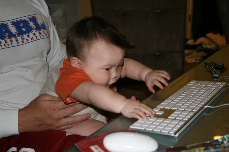 baby holding onto the keyboard and crawling beside its mom