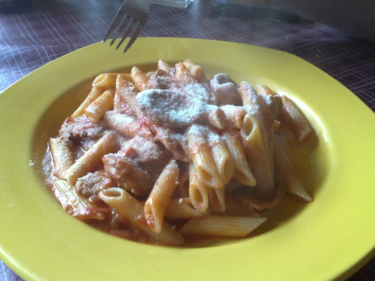 a yellow plate with pasta and meat on top