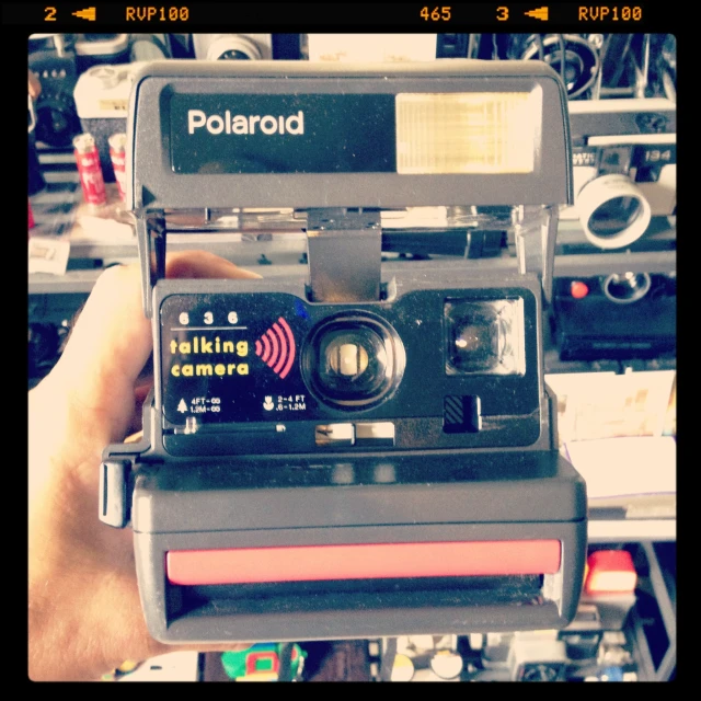polaroid with lens and matching camera case held in a shop