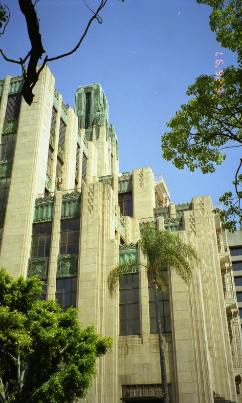 a tall brown building surrounded by trees on a clear day