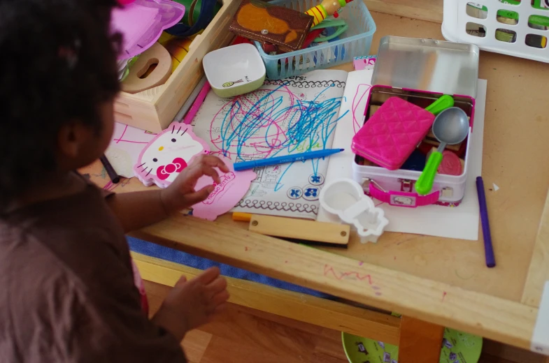 a child in a pink shirt is drawing on the desk