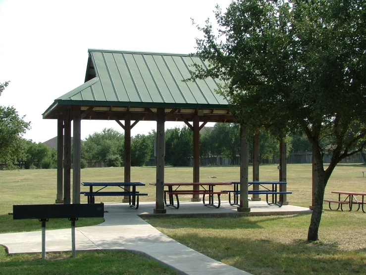 picnic tables sit underneath a large pavilion with a bench
