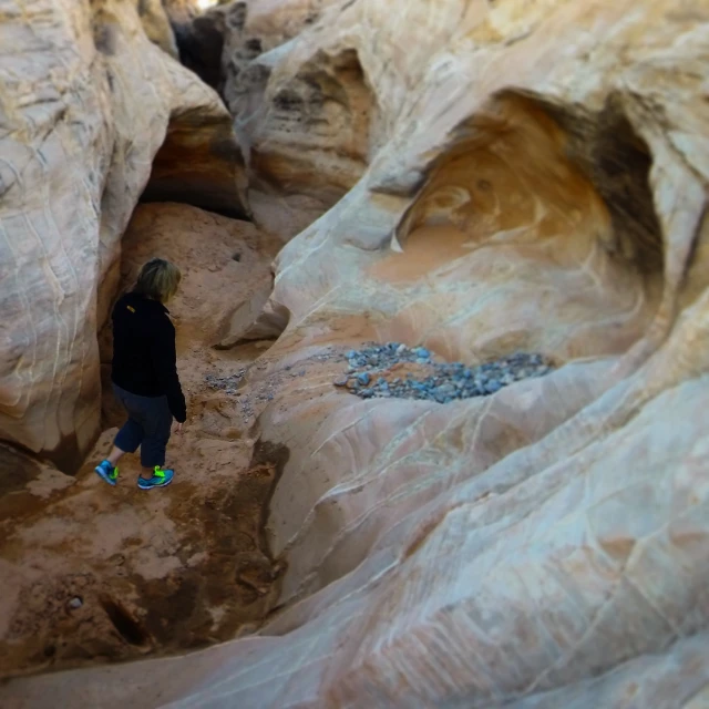 a woman walking through some rocks in a canyon