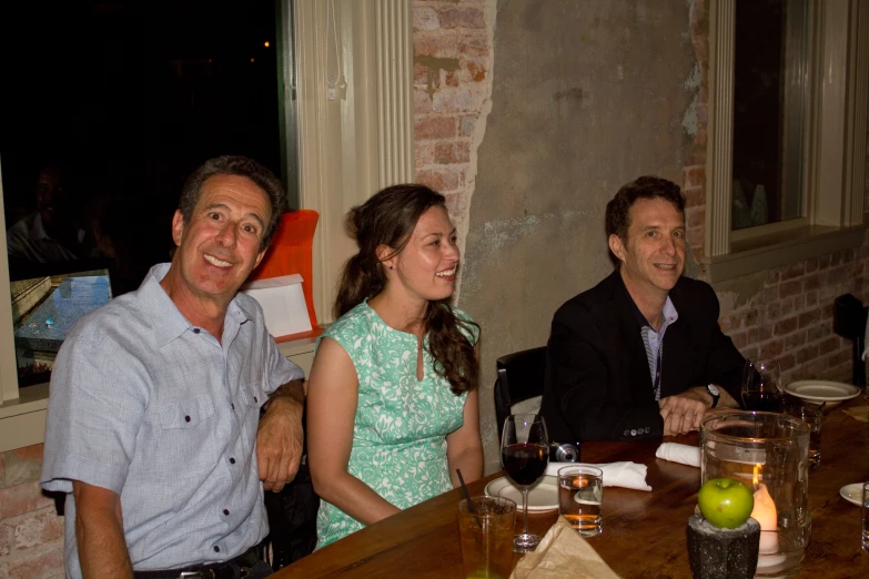 three people sitting around a table eating and drinking