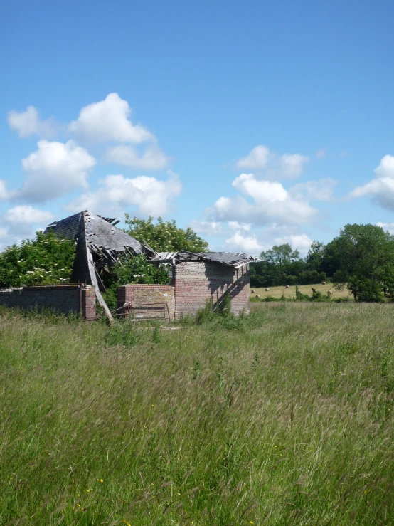 the back side of a brick building in the middle of the green field