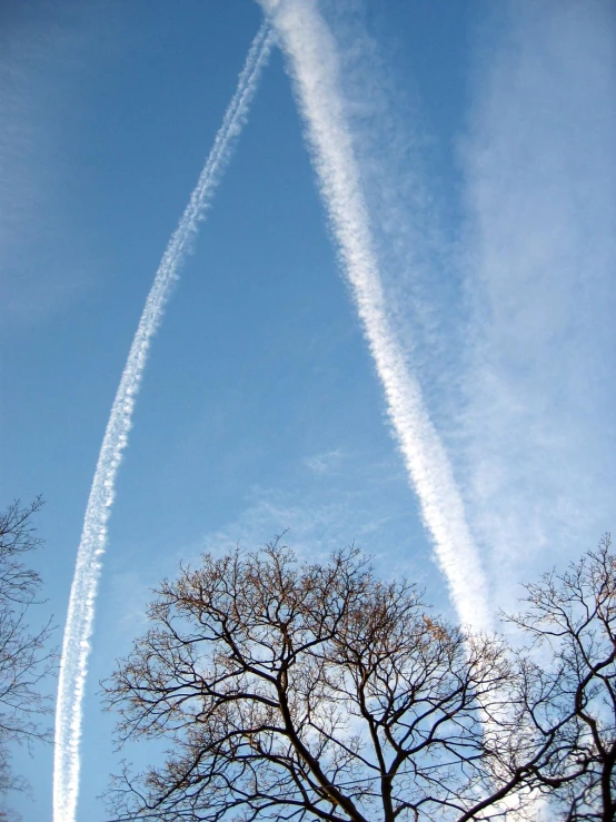 three jets flying in the blue sky near trees