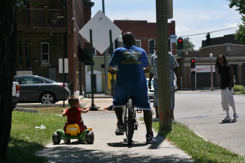 a man riding a bike with a toddler sitting on it