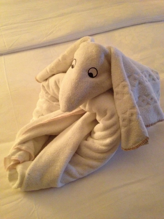 an elephant wrapped in a white towel on the bed