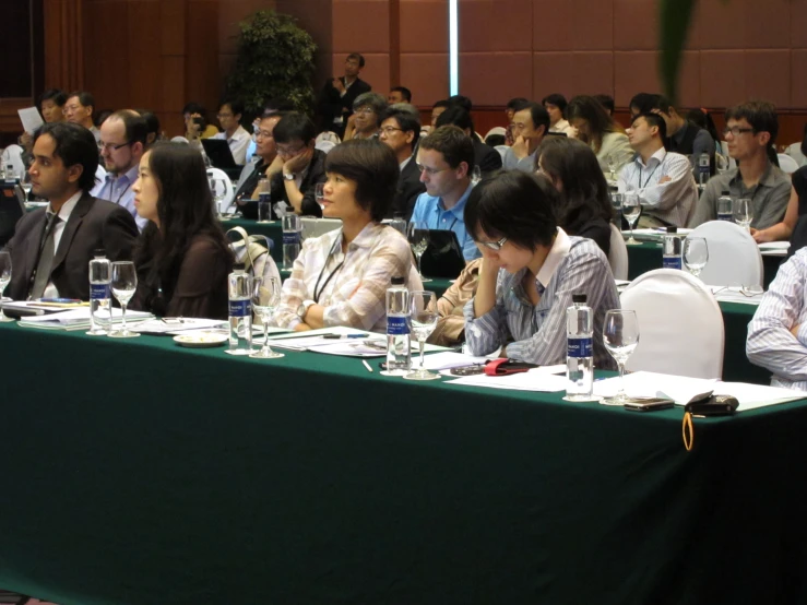 people sit at tables in a room filled with papers