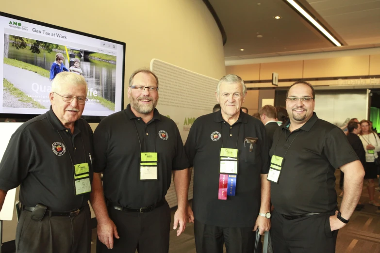 four men standing next to each other with tags on their shirts