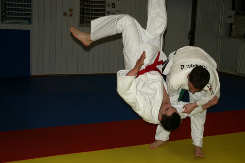 two men are in a room doing tricks on karate mats