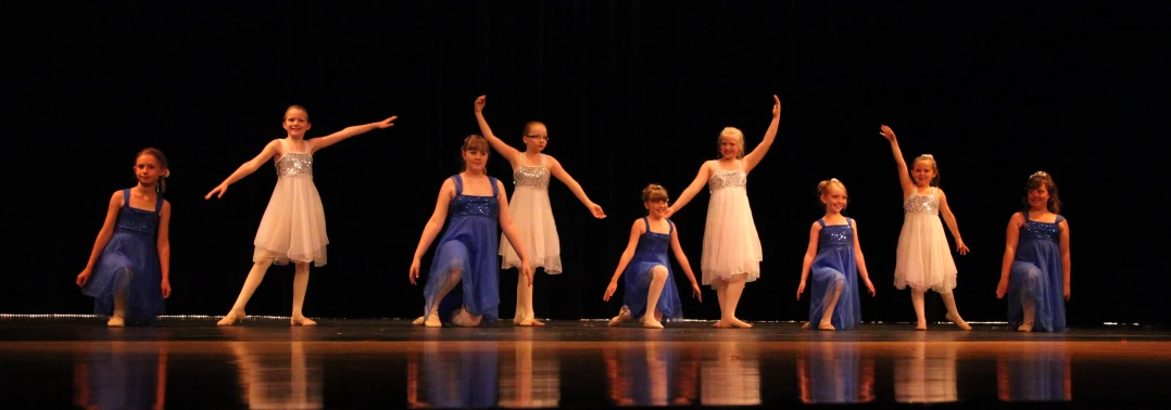 several ballet dancers with one holding their arms up in the air