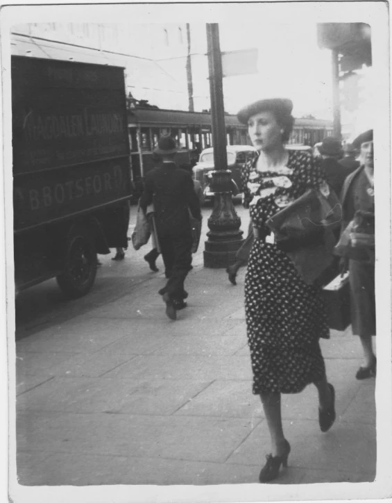 an old po of a woman in a hat walking down the street