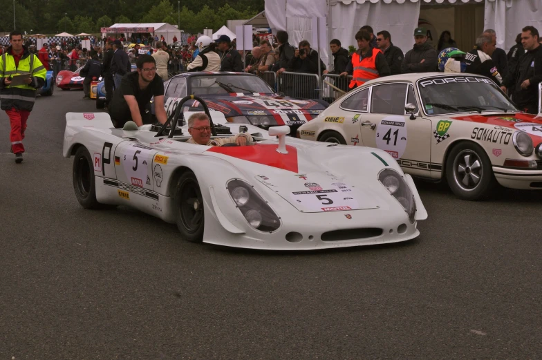 two white cars with red flags on their wheels racing in the street