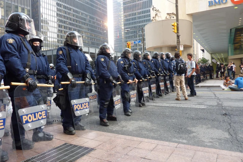 police stand behind their barricades while people gather in the city