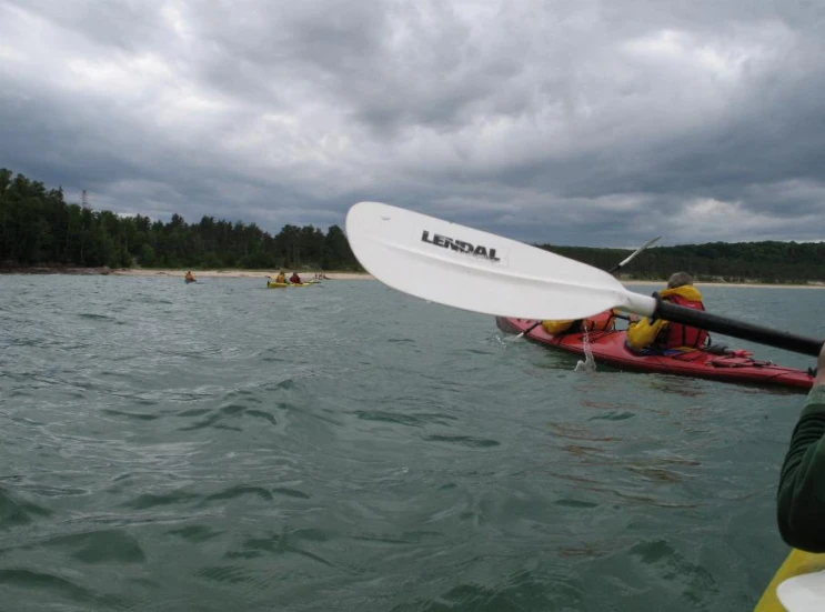 a man in the water with two people floating on top of kayaks