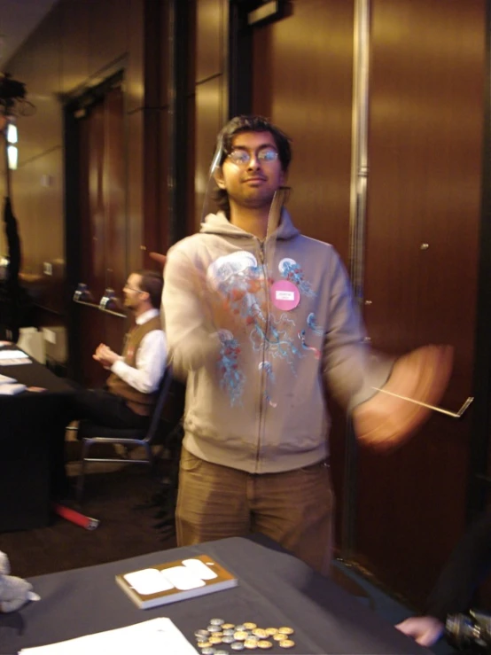 a man wearing a hoodie standing in a room with other people