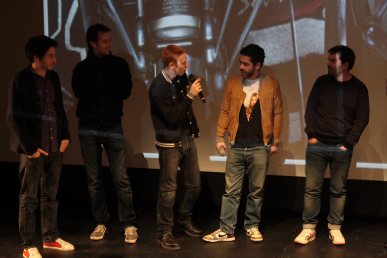 five young men standing around talking while one man takes his picture