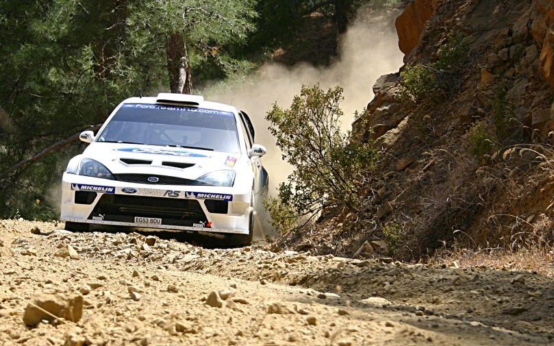 a car driving through dirt and rocks near a hill