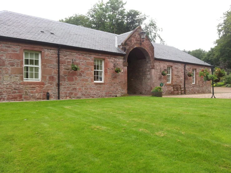 an old brick house sits in a green field