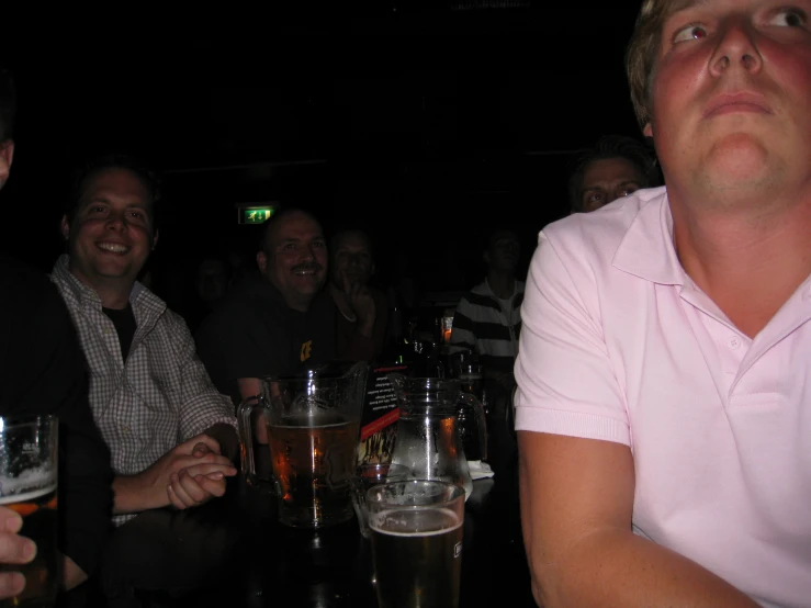 men are smiling as they sit together drinking beer