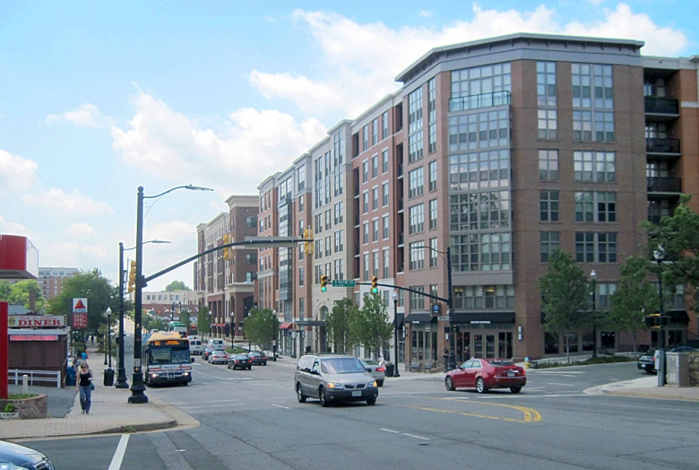 people are walking near an intersection where cars can be seen