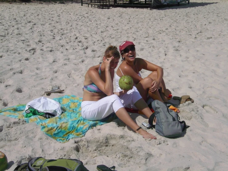 a woman and a man sitting on a towel on the beach