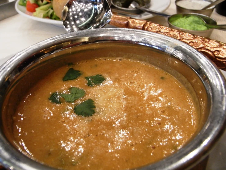 the bowl is full of soup and there are some spices on the spoon