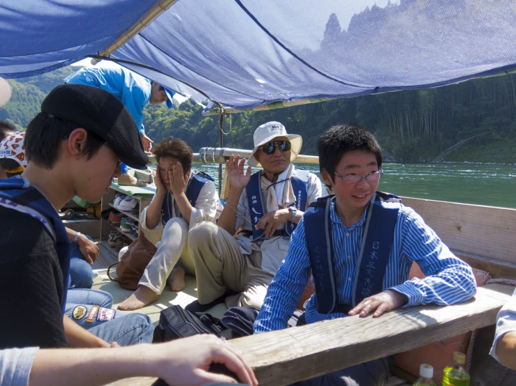 several men sitting inside of a boat on the water