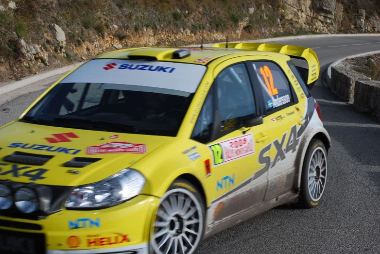 yellow subarun rally car driving around a mountain road