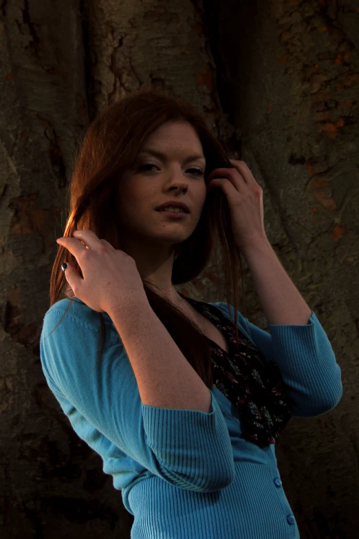 a woman leaning against a tree with a hand on her head